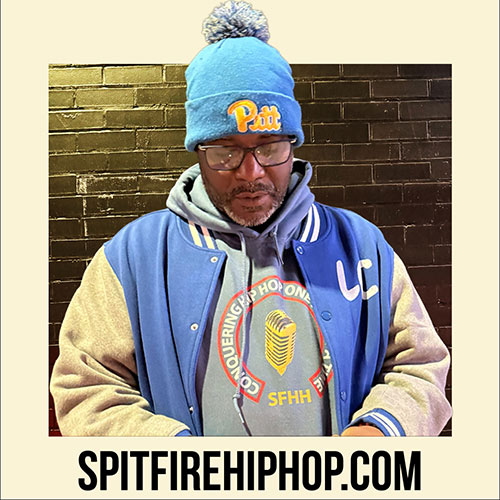 Hip-Hop artist J. Sands wearing the Conquering Hip-Hop One Mic At A Time hoodie in an urban setting, representing SpitFireHipHop culture.
