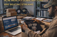 Independent Hip-Hop artist in a home studio packing merch orders while monitoring fan subscription income on a laptop, illustrating bundle economics and direct-to-fan revenue — SpitFireHipHop Corporate Corner.