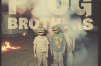 Frog Brothers IV EP cover showing three figures wearing frog masks standing in a smoky suburban street with fires burning behind them.