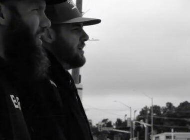 lack-and-white image of two Hip-Hop artists, Legit and HostileProd, standing side by side on a city street, wearing caps and looking forward, capturing a gritty, cinematic underground Hip-Hop aesthetic