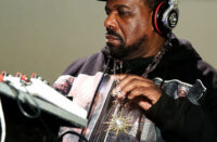 Ultra-realistic portrait of Afrika Bambaataa wearing sunglasses and a leather jacket, with bold headline “Hip-Hop Pioneer Dead” and SpitFireHipHop branding, representing breaking news of his death and legacy in hip-hop culture