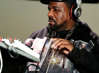 Ultra-realistic portrait of Afrika Bambaataa wearing sunglasses and a leather jacket, with bold headline “Hip-Hop Pioneer Dead” and SpitFireHipHop branding, representing breaking news of his death and legacy in hip-hop culture