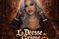 Female Hip-Hop artist with silver hair and bold makeup stands against a burning city backdrop with glowing halo light, representing the cinematic tone of La Déesse du Crime EP.