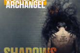 Cover art for “Shadows” by Apokalips The Archangel featuring a shadowy smoke figure with glowing eyes looming behind a man standing against a dark wall with bold gold and white typography.
