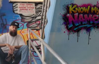 Travisty The Lazy Emcee sits beside colorful graffiti artwork in the “Know My Name” music video alongside visuals promoting the underground Hip-Hop single produced by DJ Kawon.
