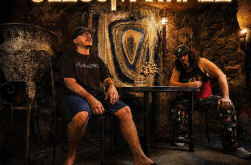 Jezus Martinez pose inside a dimly lit room with glowing gold typography promoting their EP THE SALAMANDER and the single “Hall of Mirrors.”