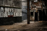 Curriculum and KHEYZINE A Mystery Darkened album cover featuring a shadowy abandoned industrial building with the album title painted across a concrete wall.
