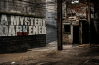 Curriculum and KHEYZINE A Mystery Darkened album cover featuring a shadowy abandoned industrial building with the album title painted across a concrete wall.