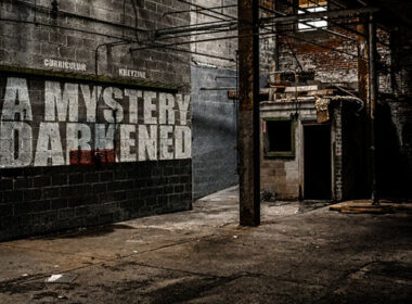 Curriculum and KHEYZINE A Mystery Darkened album cover featuring a shadowy abandoned industrial building with the album title painted across a concrete wall.